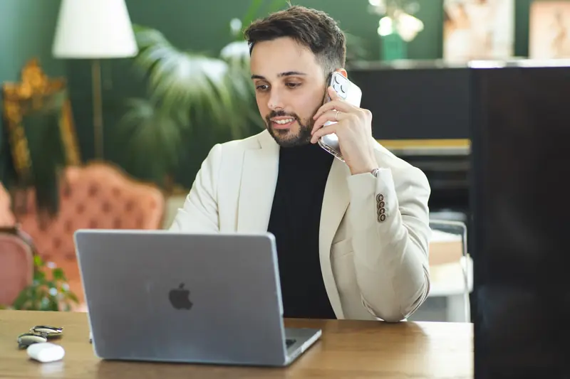 Luca Sacco al telefono con un cliente davanti al portatile